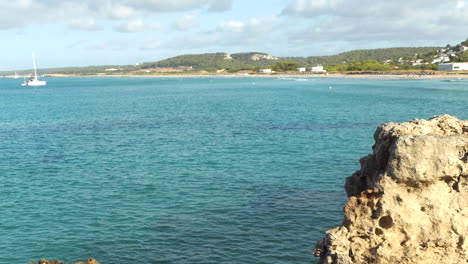 wide distant view of son bou beach the longest in menorca, clear and calm water with boats, balearic islands, spain