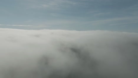 aerial flight above thick gray puffy clouds with blue sky i background