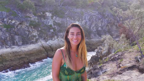 Young-Caucasian-Woman-Watching-Waves-In-The-Ocean-Turns-Head-With-Smiling-Face---North-Gorge-Walk,-Australia