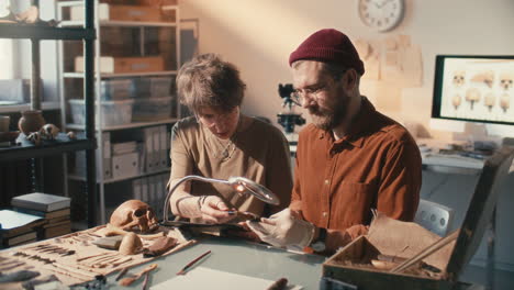 archaeologist researching artifacts with help from colleague in laboratory