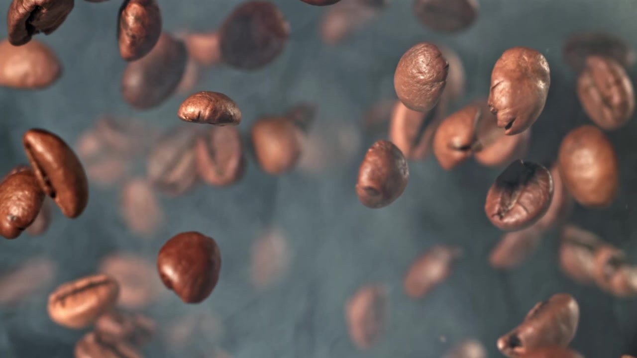 Chicchi di caffè tostati in caduta al rallentatore con fumo
