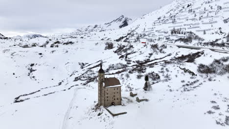 old spittel hospiz at the black asphalt road over the with snow covered simplon pass on a cloudy day