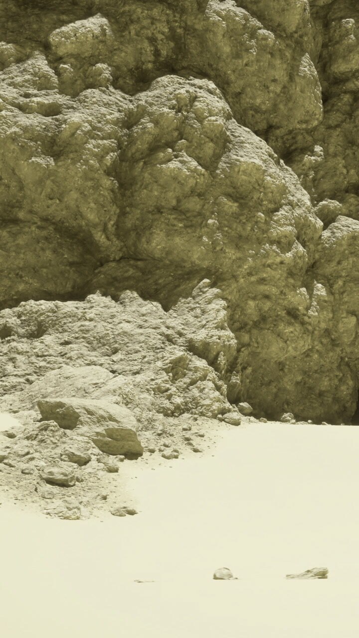 Rocky formation beside sandy area in desert under bright sunlight