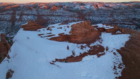 drone shot pulling back to reveal snow covered red rock