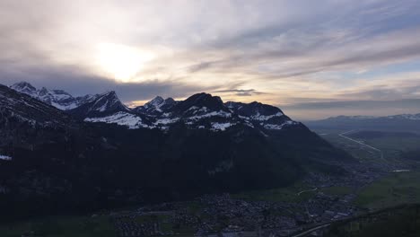 drone clip showing beautiful sunrise behind rocky snowy alpine mountains