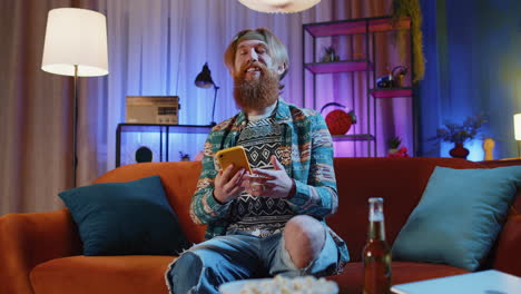 hombre hippie guapo en casa usar teléfono inteligente escribir navegación wow sí descubrió gran gran victoria celebrar