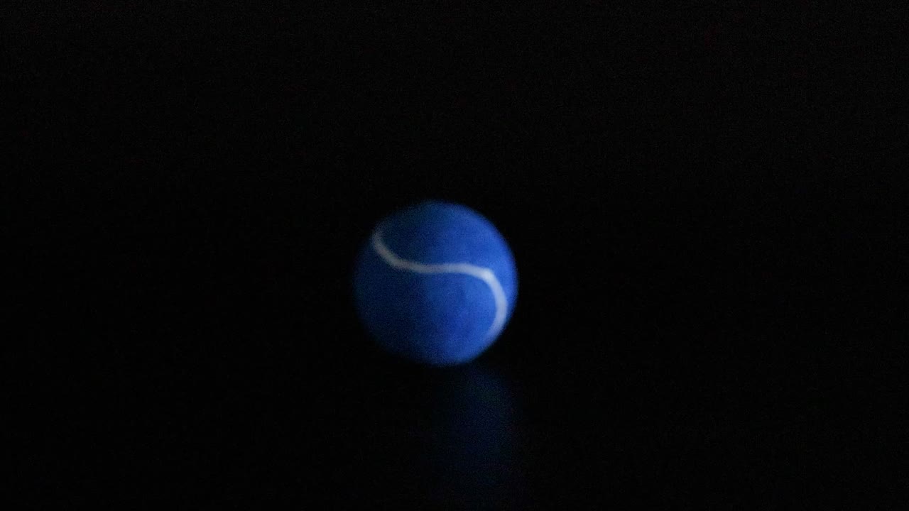 A vibrant blue tennis ball bounces repeatedly in slow motion against a dark, minimalist background