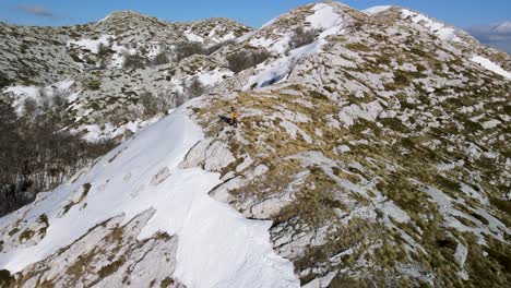 Man-hiking-alone-at-peak-of-snowy-mountain,-sunny-day,-Sveti-Jure,-Park-prirode-Biokovo