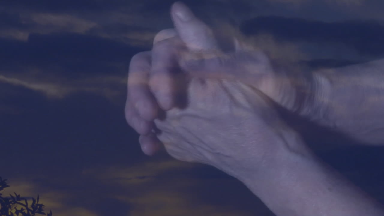 Clasped hands with cloudy sky background, conveying unity and hope