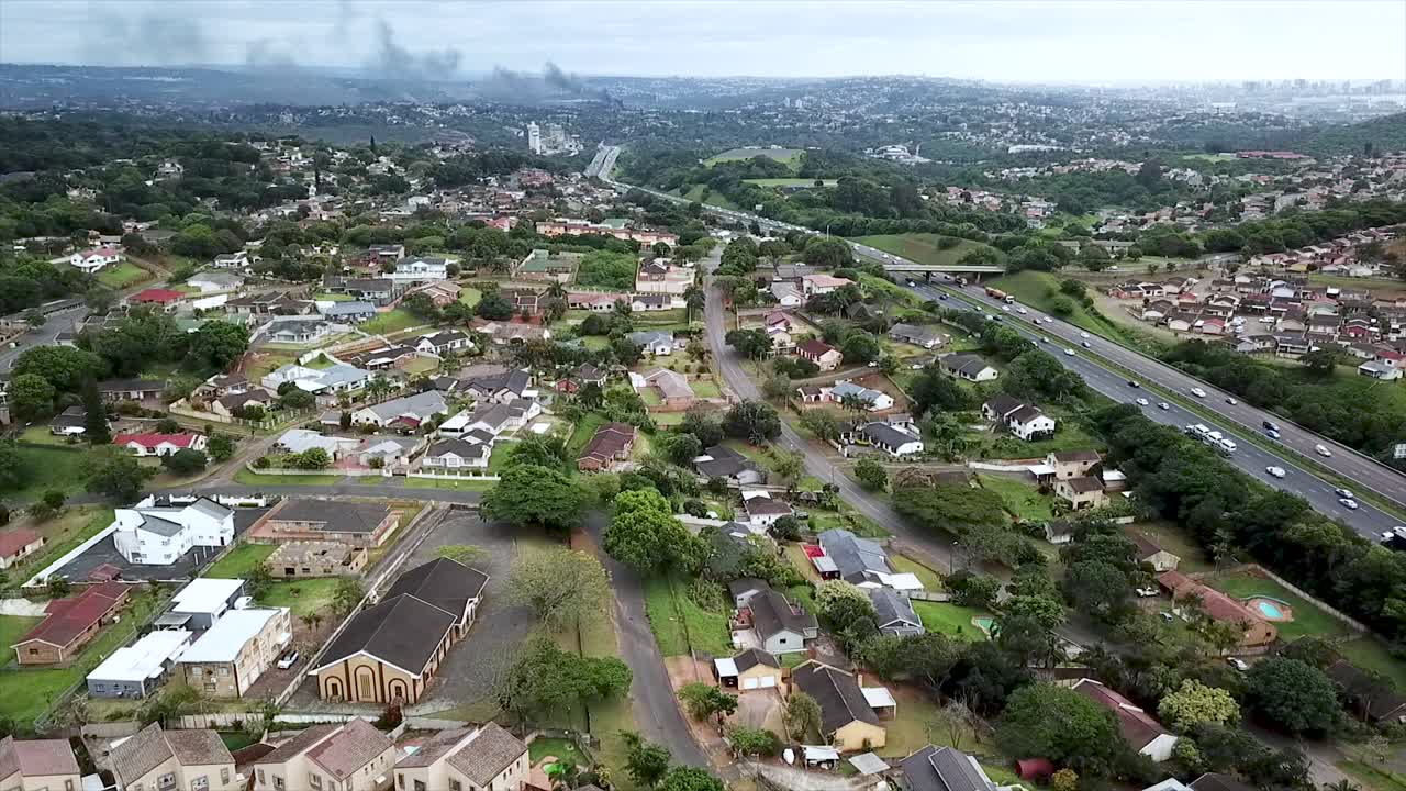 imágenes aéreas de un avión no tripulado volando sobre casas residenciales con vistas a una autopista concurrida con tráfico en movimiento en un suburbio de yellow wood park durban