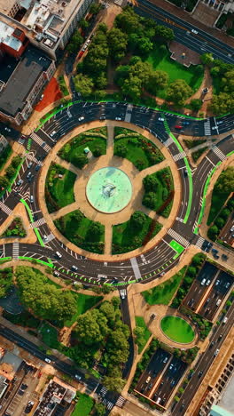 transport moves by the roundabout surrounded by lush greenery. top view. lively roads of philadelphia. vertical video