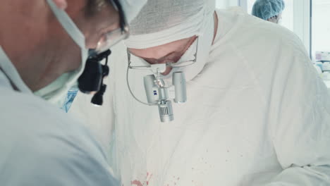 surgeons with binoculars perform surgery. doctor removes chest tube with instrument preparing patient for closing incision in operating room