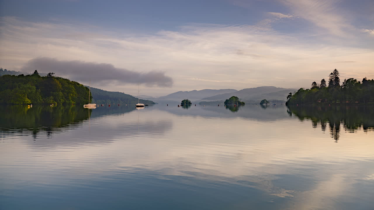 Lake District sunrise landscape time lapse at Lake Windermere. 4k timelapse of perfect reflection of sailing boats and beautiful clouds moving in Cumbria, England in typical relaxing British scenery
