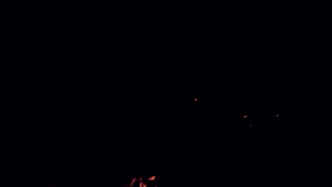 brasas brillantes se elevan hacia la oscuridad del cielo nocturno desde una fogata