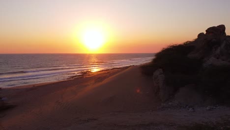 Toma-Aérea-Océano-Puesta-De-Sol-Amarillo-Luz-Del-Sol-Llamarada-Drone-Disparo-Volar-Sobre-Una-Duna-De-Arena-Acantilado-Costero-En-Un-Resort-De-Playa-Viajar-A-La-Aventura-Marina-En-Qatar-Naturaleza-Resort-De-Playa-Atracción-Turística-Aventura