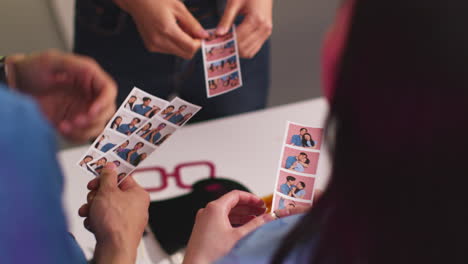 close up of a group of friends having fun looking at prints from photo booth with props 10