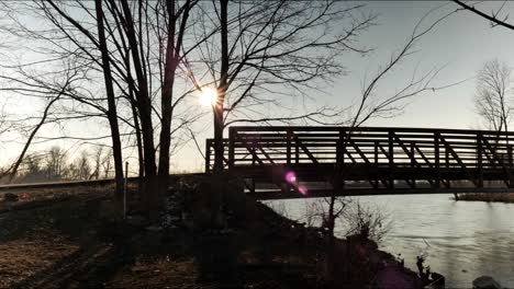 Sun-setting-behind-bridge-over-river.-Time-lapse