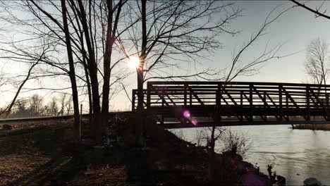 sun setting behind bridge over river. time lapse