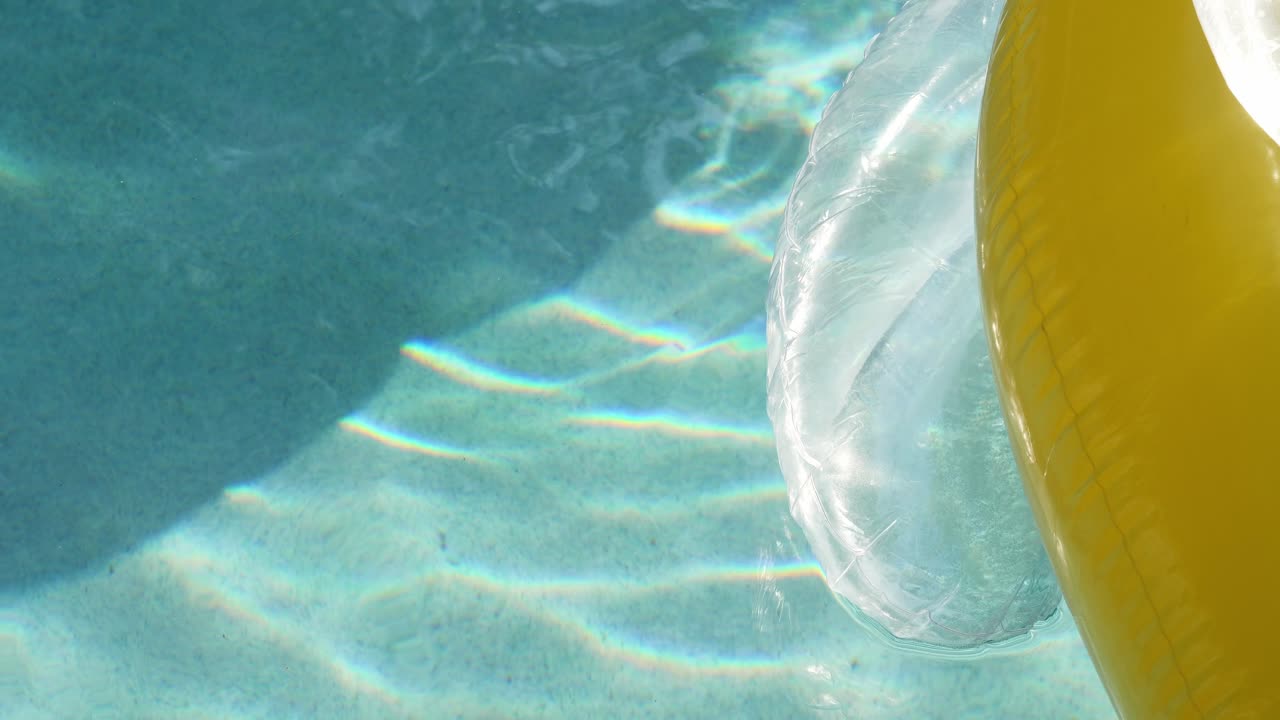 Ripples of light in a sunny pool with a yellow float in slow motion