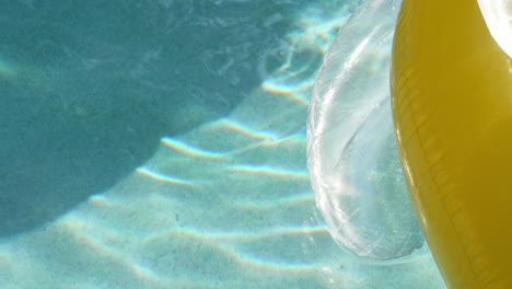 ripples of light in a sunny pool with a yellow float in slow motion