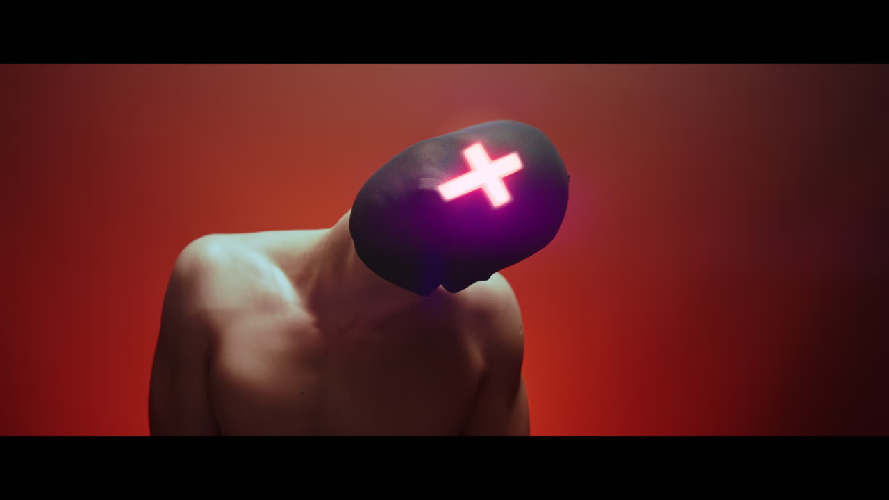 Masked man with cross of light glowing on his face moves slowly