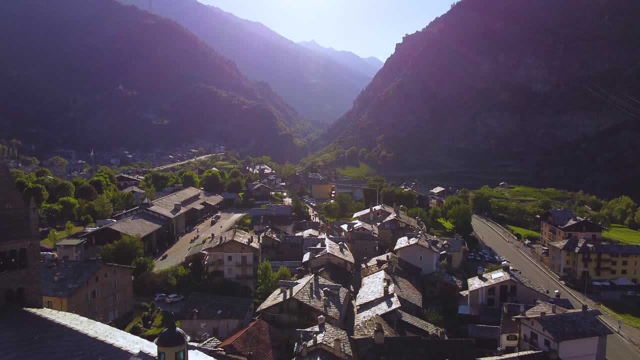 Paese delle Alpi italiane in una giornata di sole, vista aerea con drone con movimento all'indietro