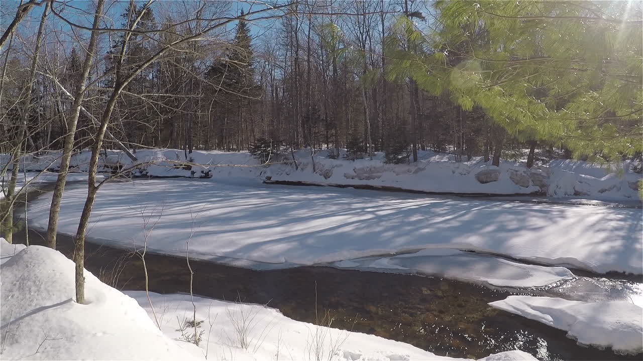 Slow panning shot of a peaceful stream with snow covered rocks in winter in New Hampshire