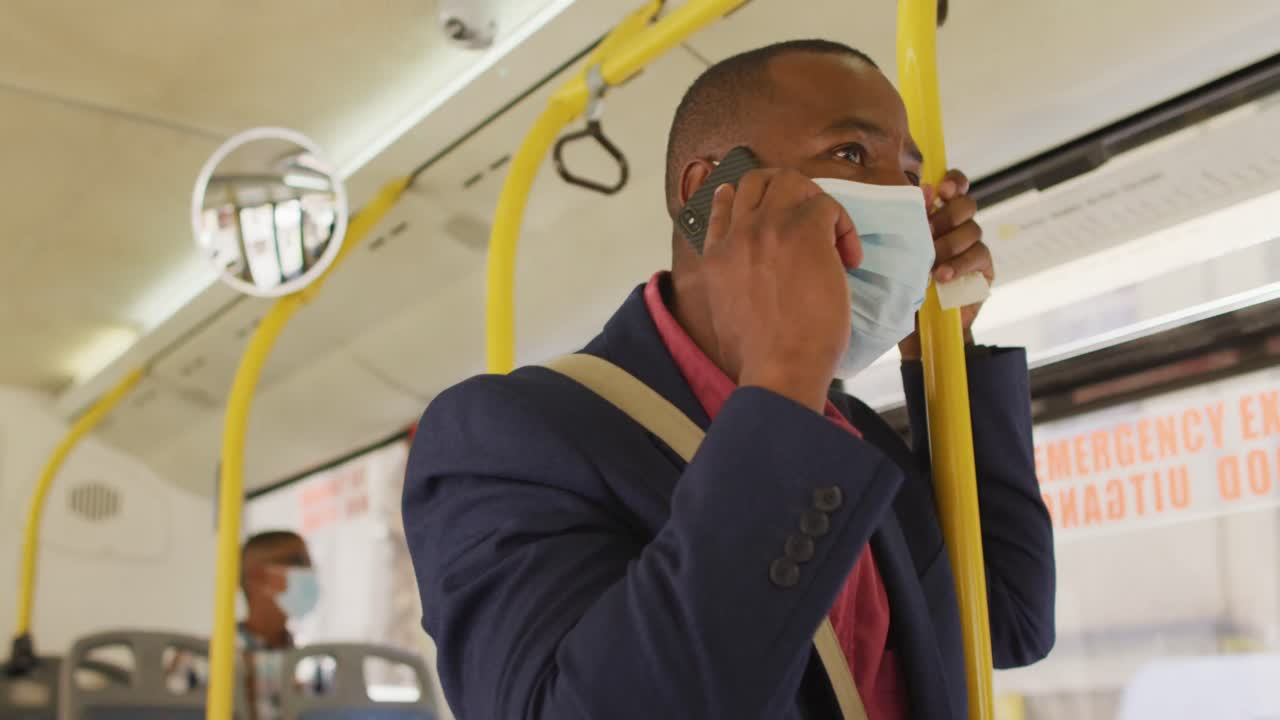 버스에서 스마트폰을 사용하여 얼굴 마스크를 쓰고 있는 도시에 있는 아프리카계 미국인