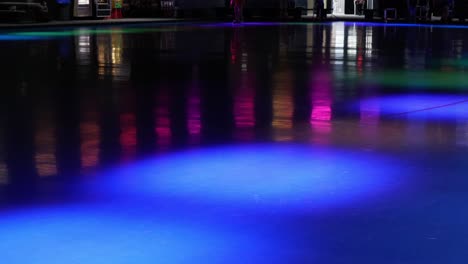 not very busy roller skating rink with skaters rolling around the brightly colored flashing lights of the event venue - in cinema 4k (30fps slowed from 60fps).