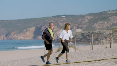 Un-Hombre-Y-Una-Mujer-Maduros-Sonrientes-Corriendo-En-La-Playa-En-Un-Día-De-Verano