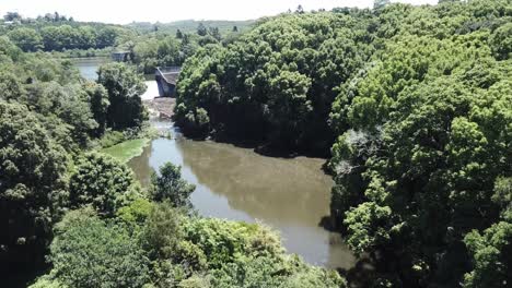 Drone-aerial-rising-to-reveal-a-dam-amongst-nature-with-trees-all-around