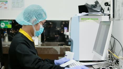 Doctor using computer in medical room. Doctor in black shirt sitting at work in Hospital. wearing a mask