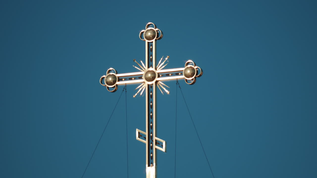 Elegant metallic church cross glowing under clear blue sky
