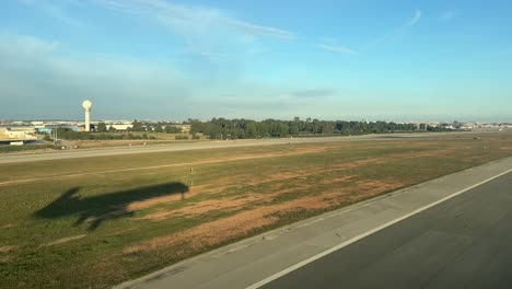 unique pilot point of view during a jet landig at the runway , with the side view of the shadow of the plane