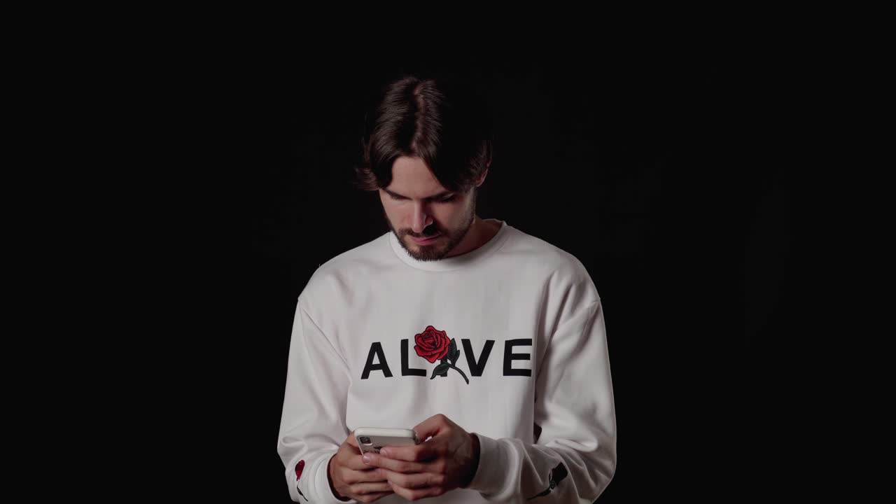 un joven moderno usando y escribiendo en su teléfono inteligente, fondo ancho y negro