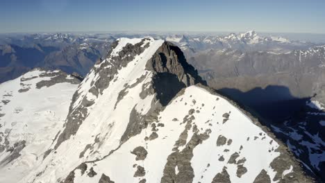 huge mountain with rock and snow on the peak amongst a spectacular mountain range high above the valleys in new zealand during sunrise