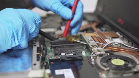 vista estática de cerca de un diagnóstico de una vieja computadora portátil rota con equipo especial y guantes protectores