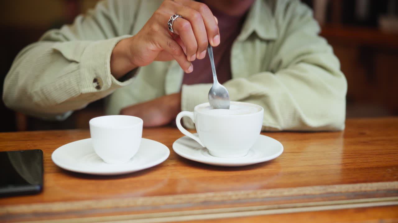 A person stirring coffee in a cafe
