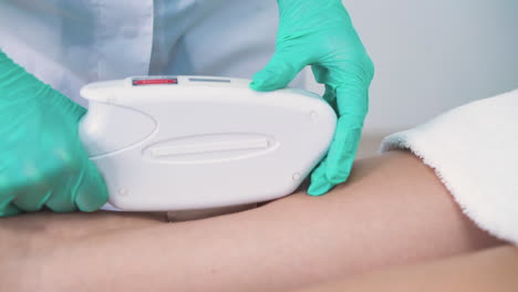 cosmetologist in gloves does laser epilation to girl client