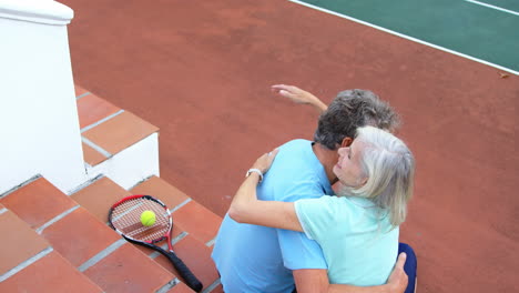 senior couple hugging on tennis court stairs 4k