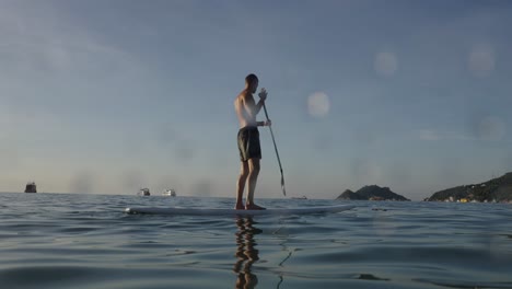 man paddleboarding on the ocean with distant islands