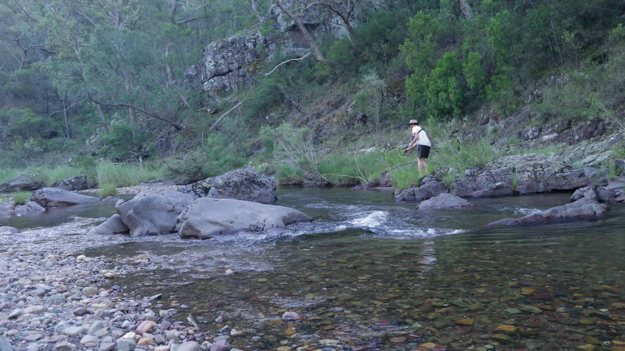 한 남자가 오스트레일리아의 야생에서 강에서 오징어를 잡습니다.
