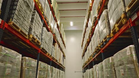 aerial view of a warehouse shelfs full of goods ready for export - reverse, drone shot