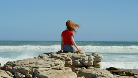 Woman-sitting-on-a-rock-and-looking-at-the-ocean-waves-4k
