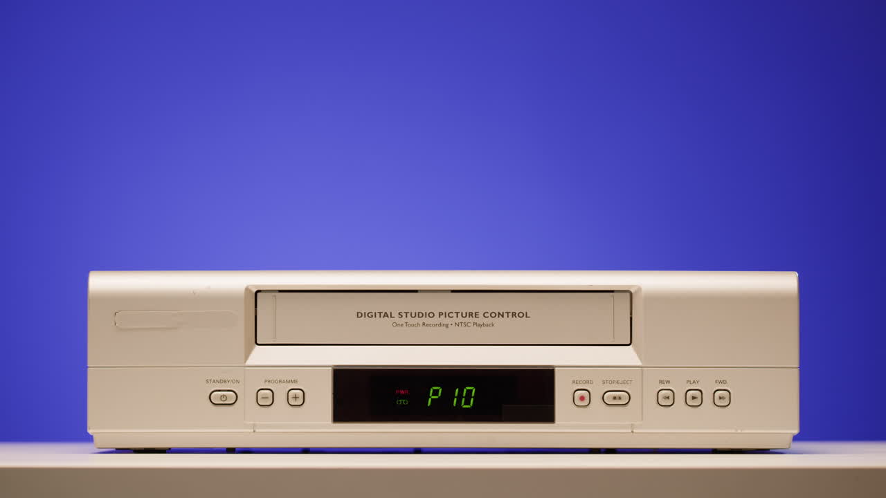 Hand holding VHS tape on a vintage VCR