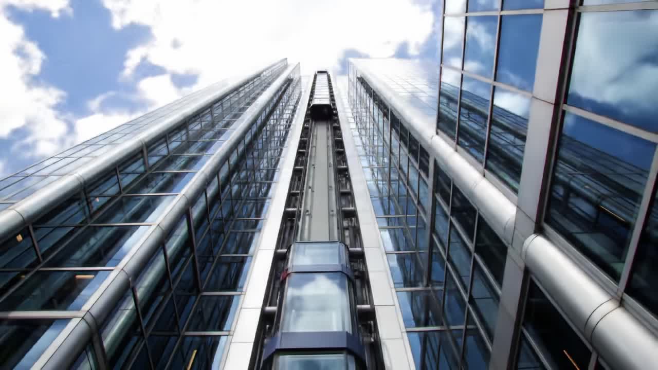 A Captivating View of Modern Architecture: Exploring the Sleek Design of a High-Rise Building with Elevated Elevators Against a Dramatic Sky