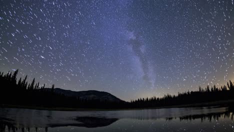 a mesmerizing time-lapse video captures star trails over a serene lake, shot from a low angle