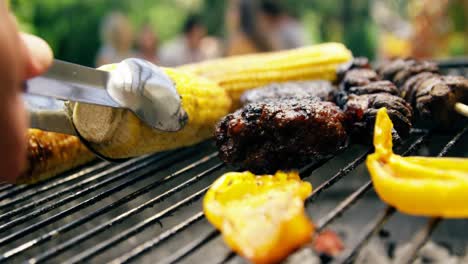 hombre asando maíz, carne y verduras en la barbacoa