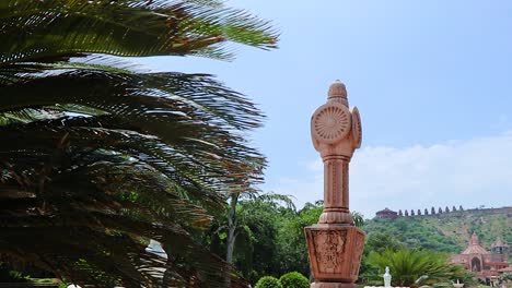 artistic-red-stone-jain-god-holy-pillar-with-bright-blue-sky-at-morning-from-unique-angle-video-is-taken-at-Shri-Digamber-Jain-Gyanoday-Tirth-Kshetra,-Nareli,-Ajmer,-Rajasthan,-India