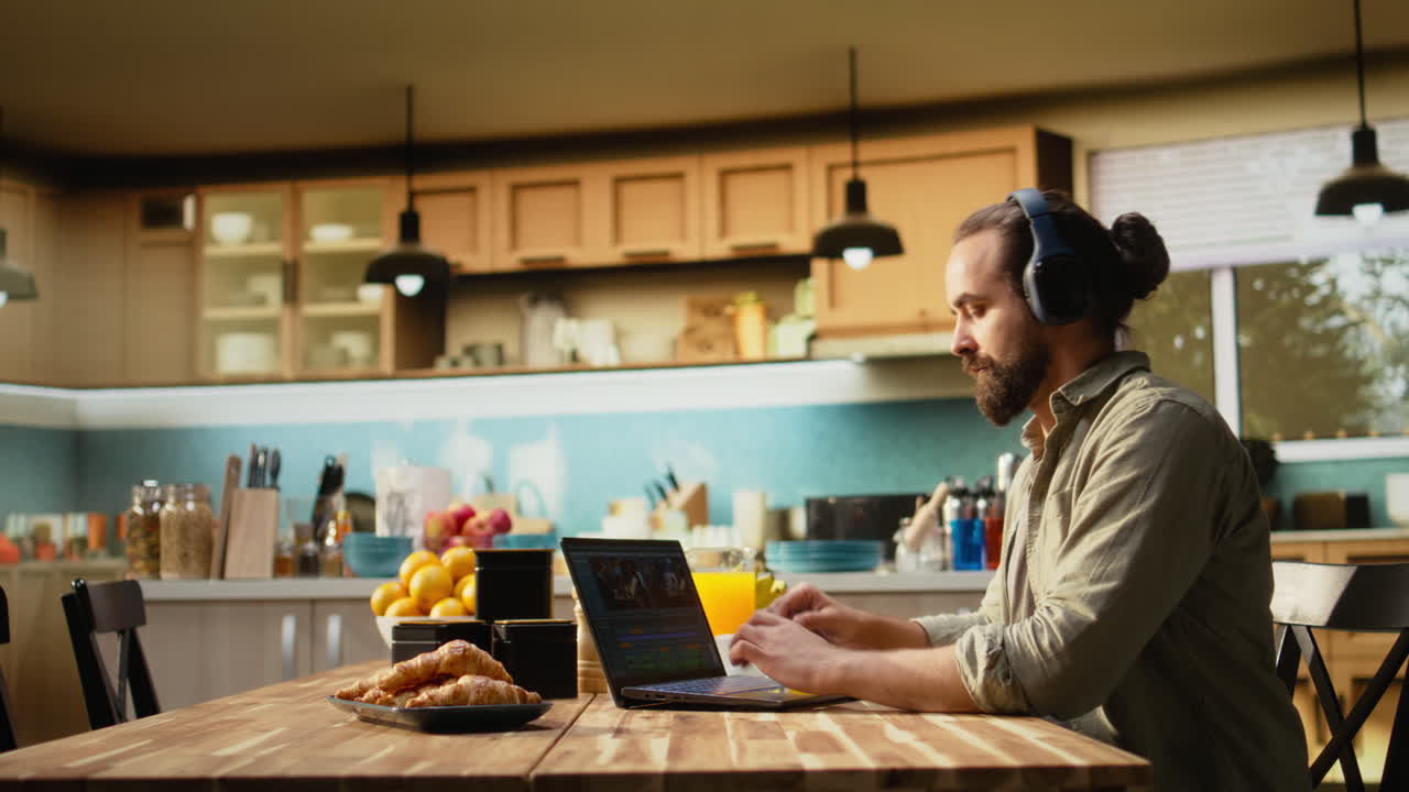 Man editing cinematic video content at home at a kitchen table